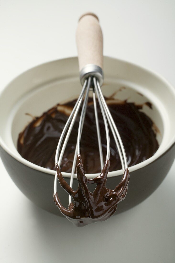 Remains of chocolate sauce in pot and on whisk