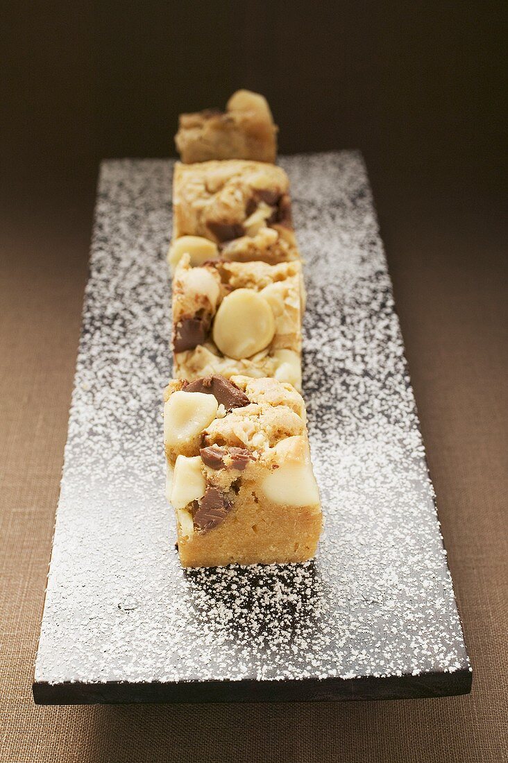 Kleine Stücke Schokokuchen mit Macadamianüssen auf Platte