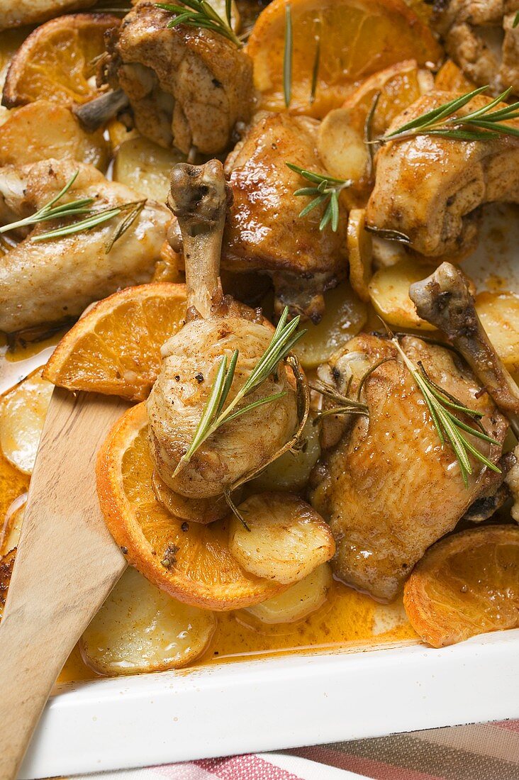 Chicken pieces with oranges and rosemary on baking tray