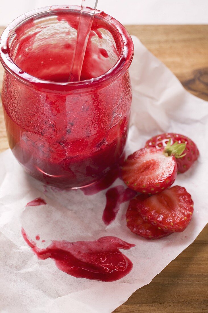 Strawberry jam and fresh strawberries on paper