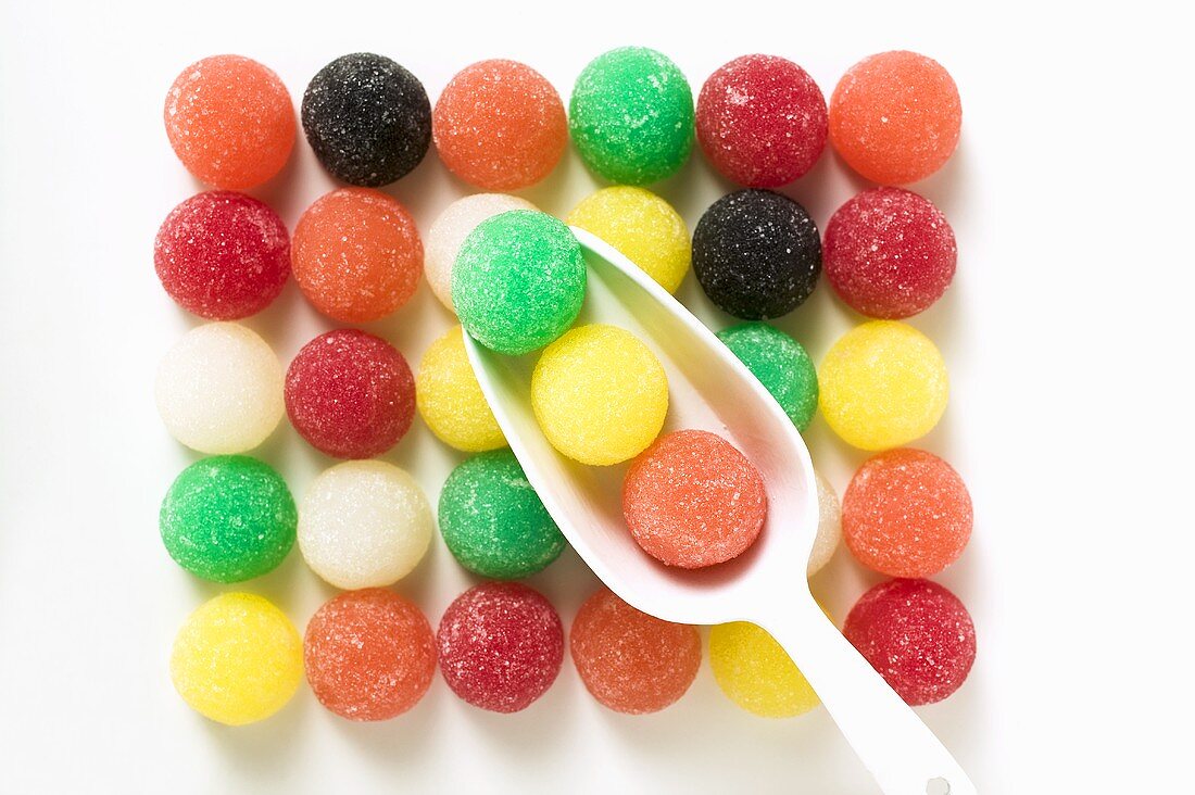 Coloured jelly sweets in rows with scoop