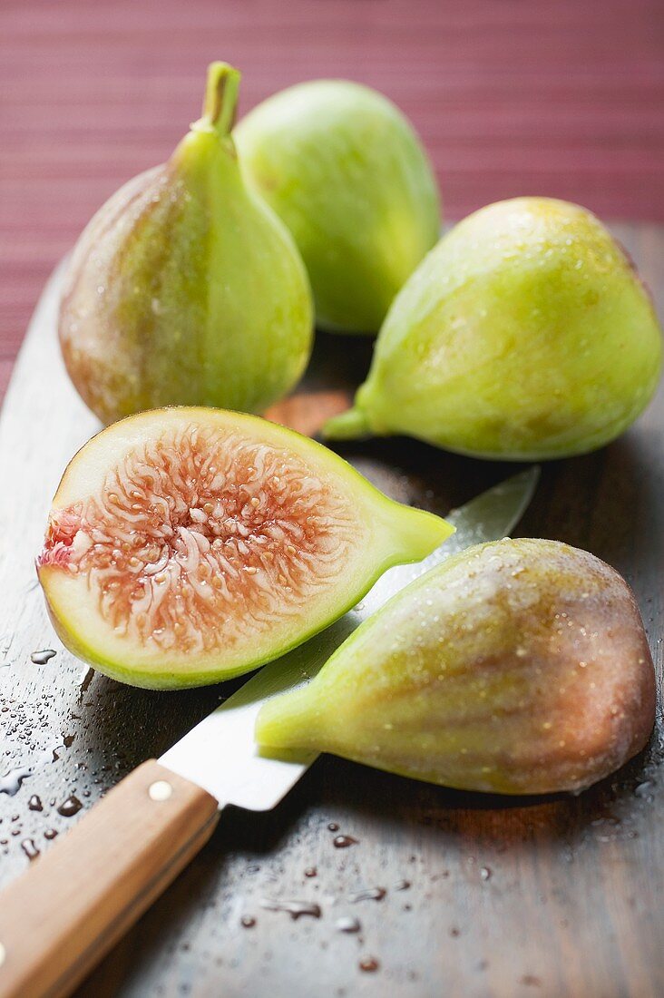Three whole figs and two fig halves with knife
