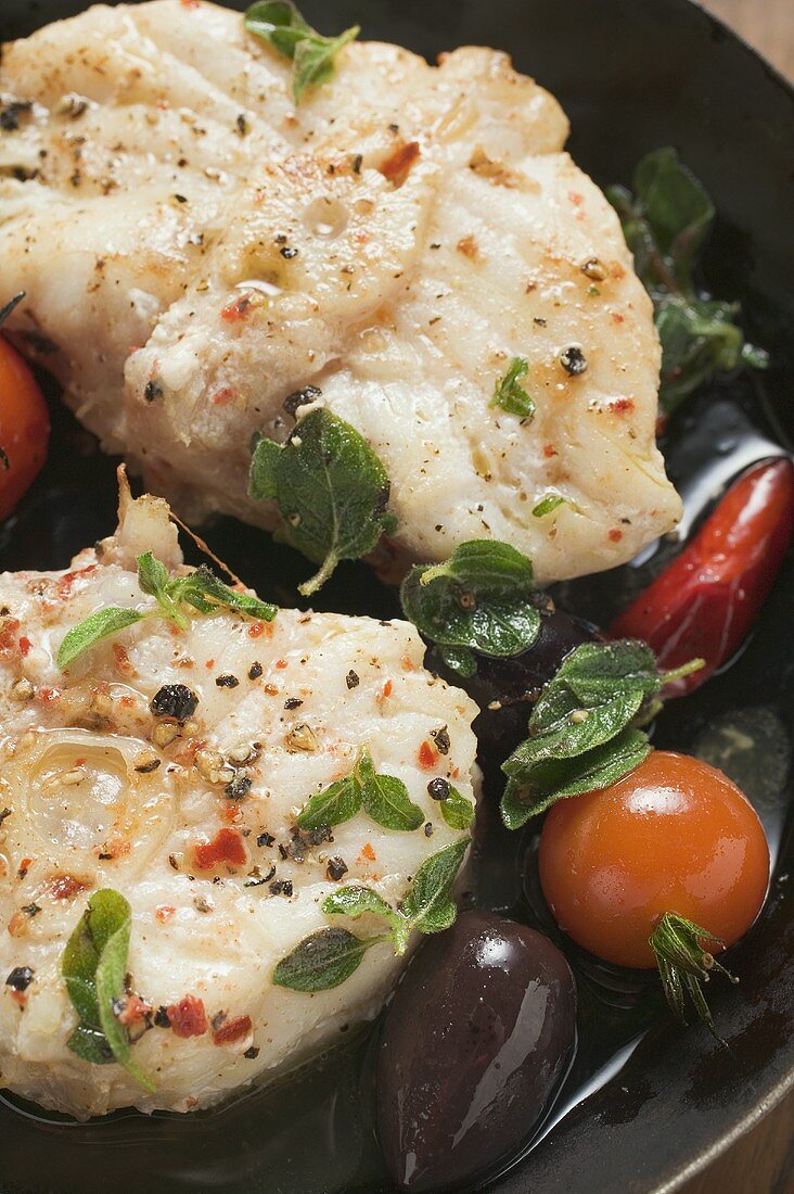 Monkfish cutlets with cherry tomatoes & olives in frying pan