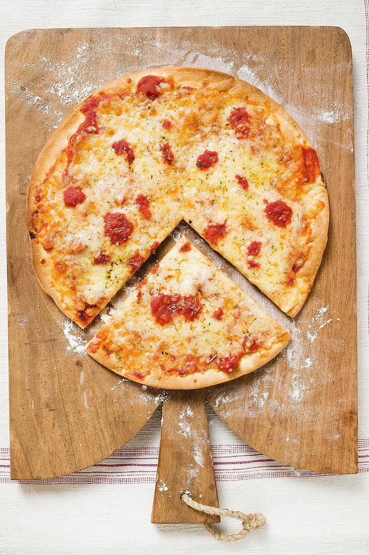 Pizza Margherita, a slice cut, on chopping board