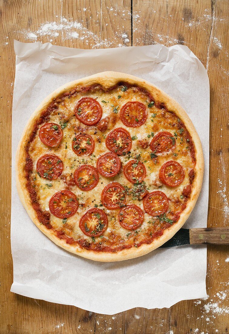 Pizza mit Tomatenscheiben, Käse und Oregano auf Papier