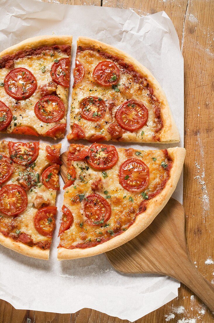 Pizza mit Tomatenscheiben, Käse und Oregano (geviertelt)
