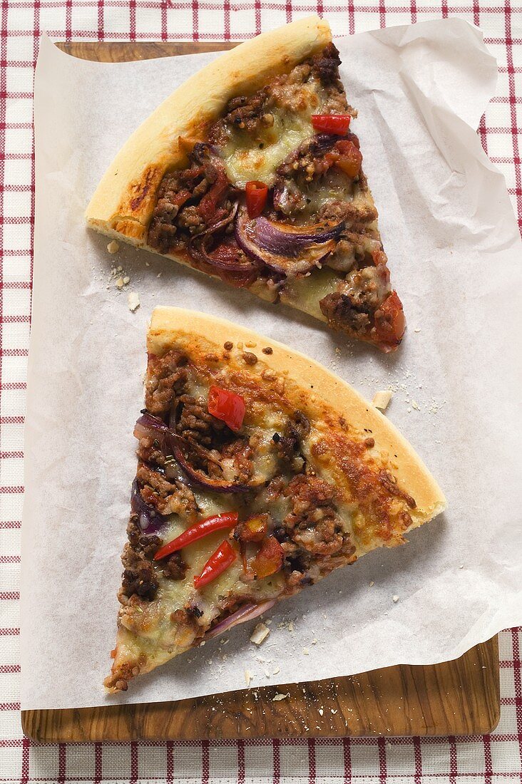 Two slices of mince and onion pizza on paper