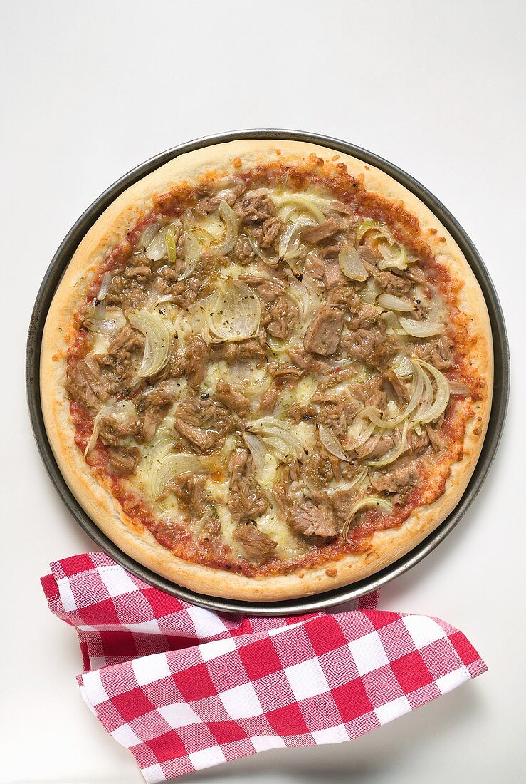 Thunfisch-Zwiebel-Pizza, daneben karierte Serviette