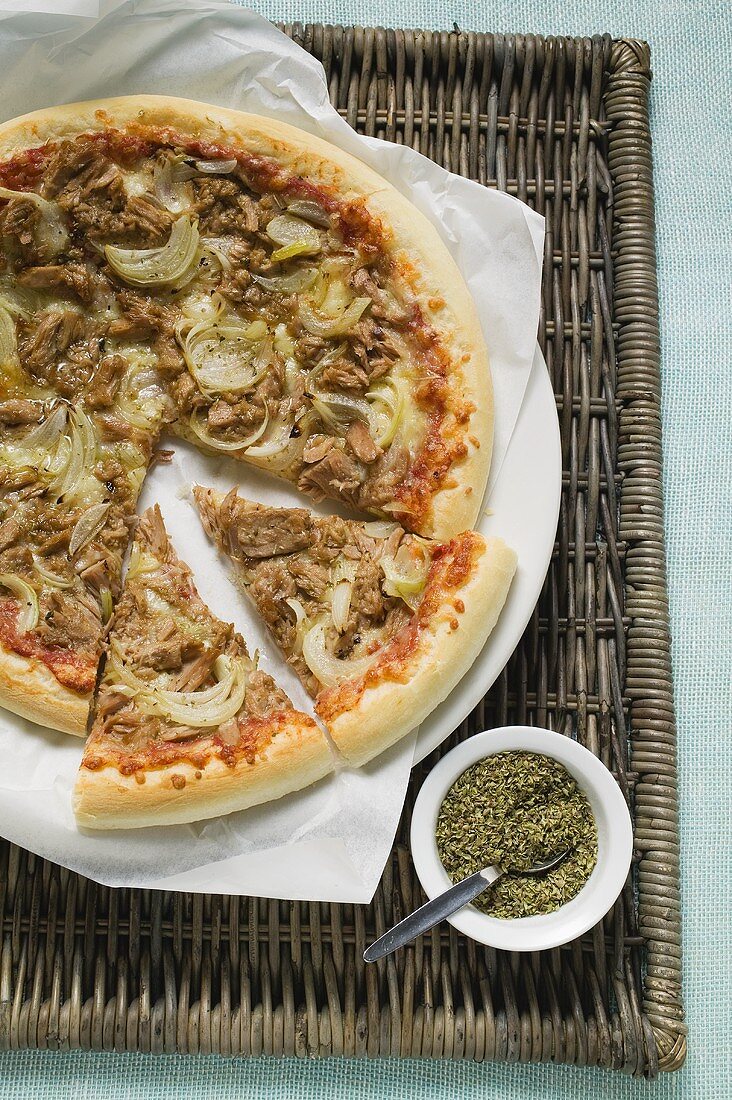 Thunfisch-Zwiebel-Pizza, angeschnitten, daneben Oregano