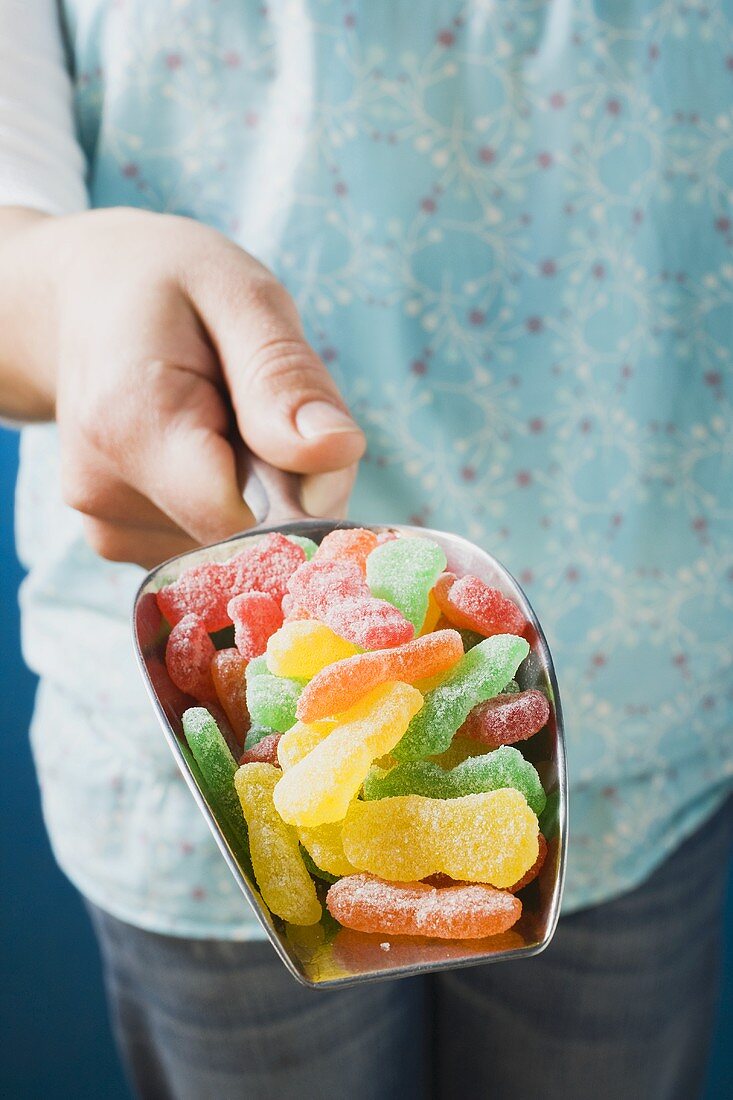 Hand hält Schaufel mit Geleebonbons