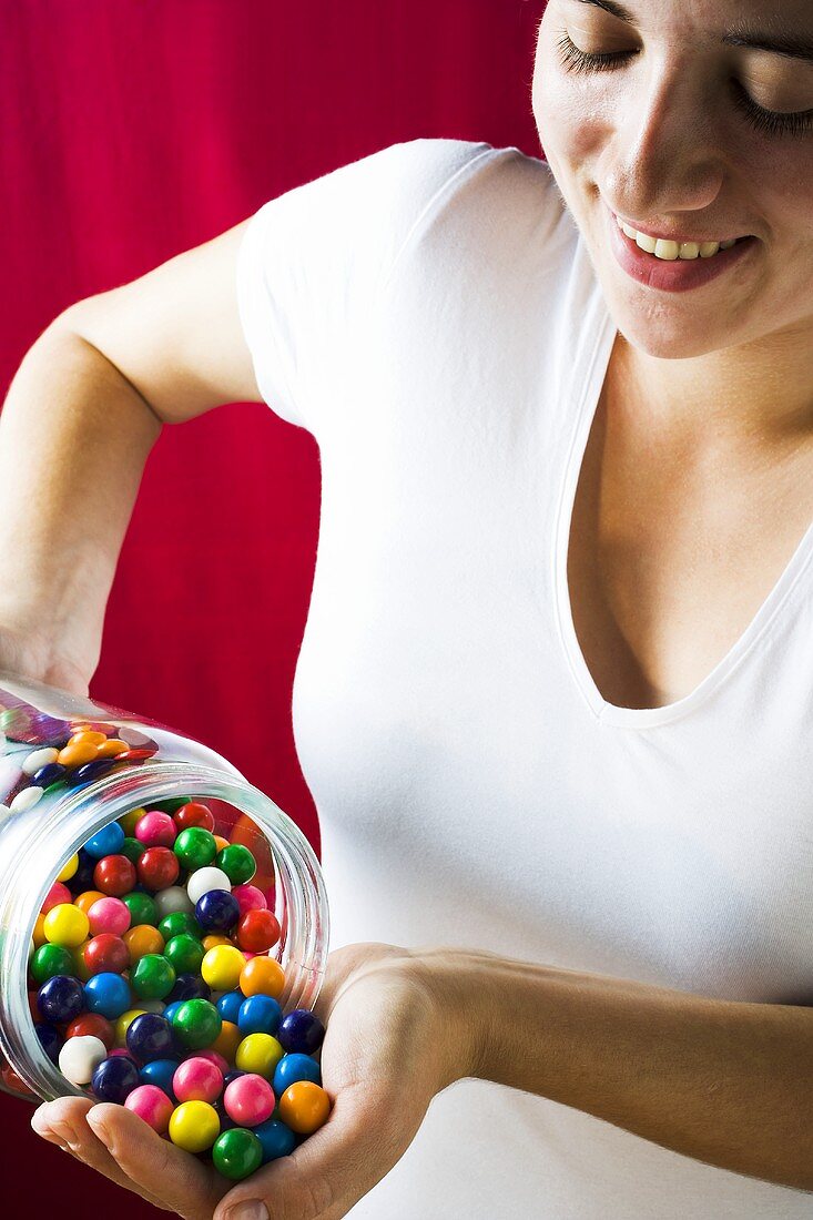 Woman tipping bubble gum balls out of a jar into her hand