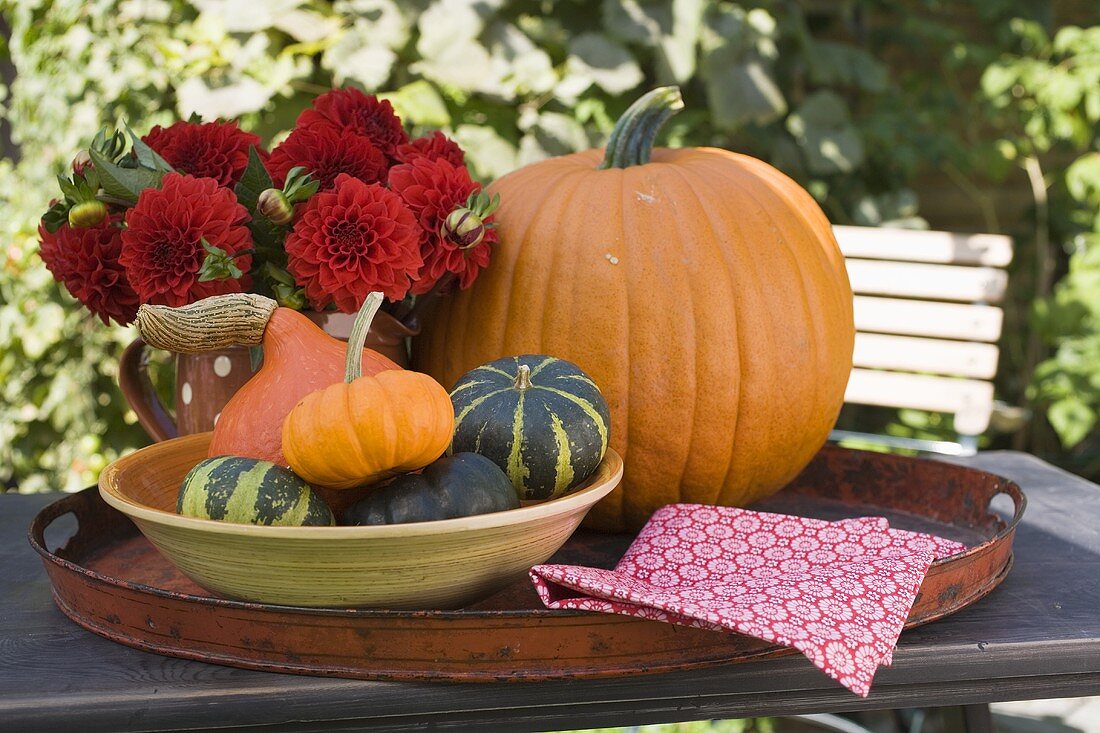 Pumpkins, squashes and flowers on table in the open air