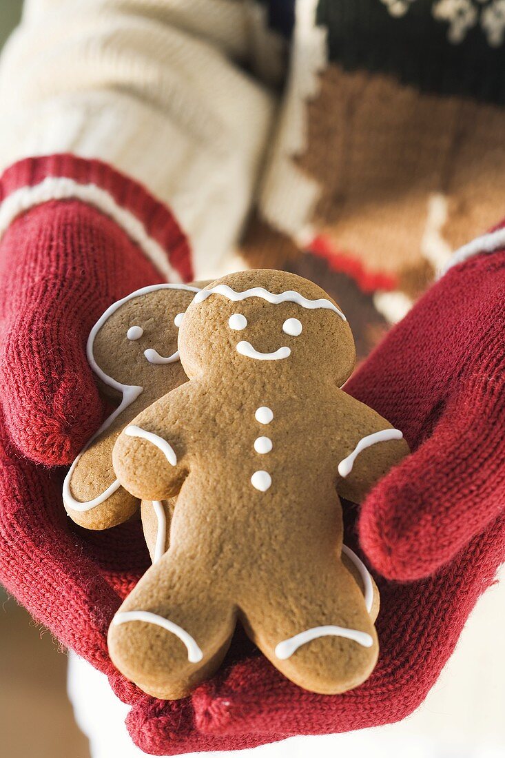 Hands in woollen gloves holding gingerbread men