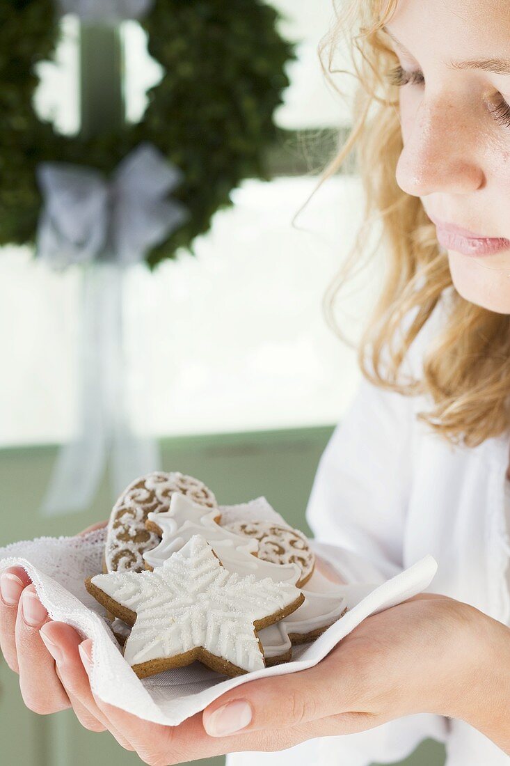 Blond girl holding assorted gingerbread biscuits on napkin