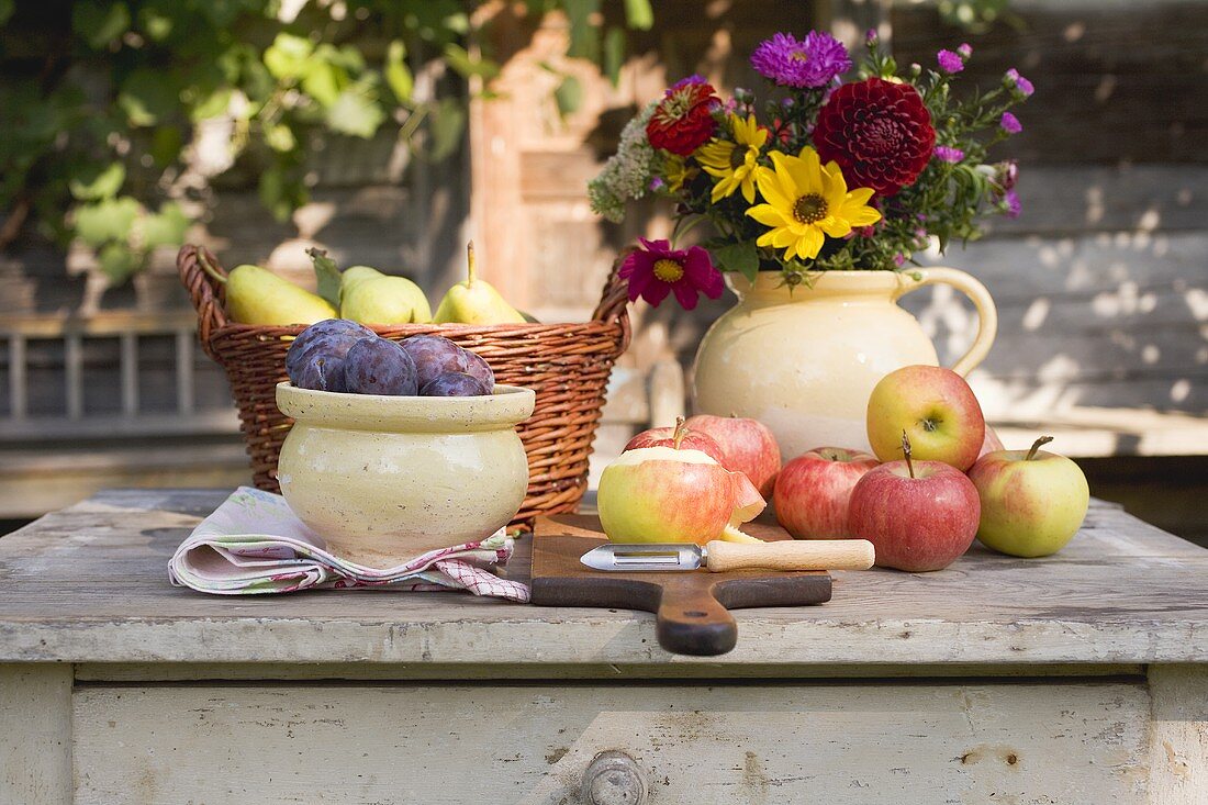 Rustic fruit still life on garden table in front of farmhouse