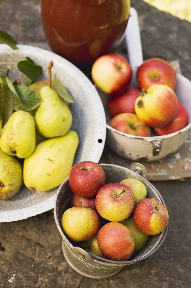 Fresh pears and apples in containers on stone wall