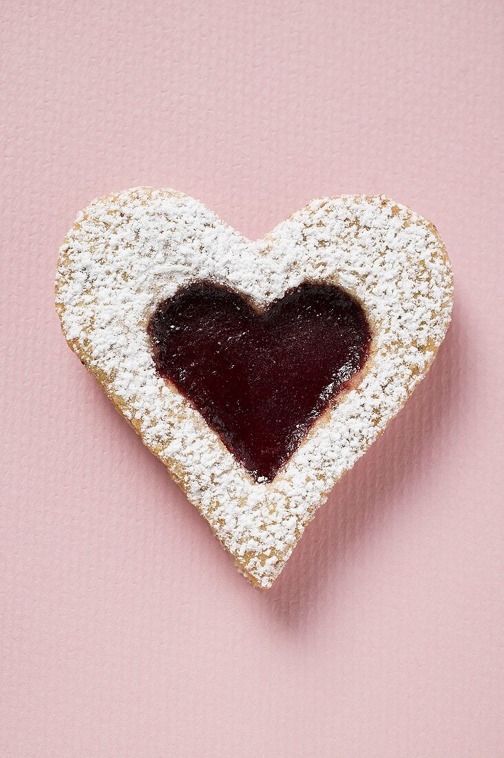 Heart-shaped biscuit with raspberry jam and icing sugar