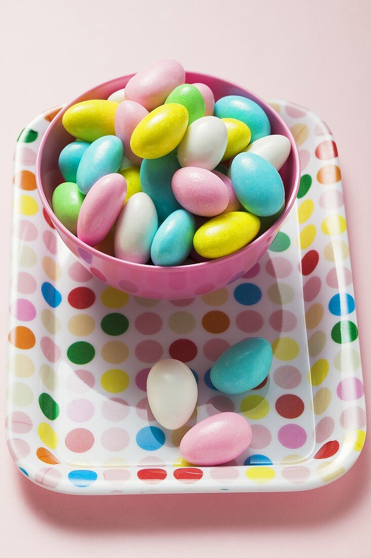 Coloured sugared almonds in pink bowl on tray