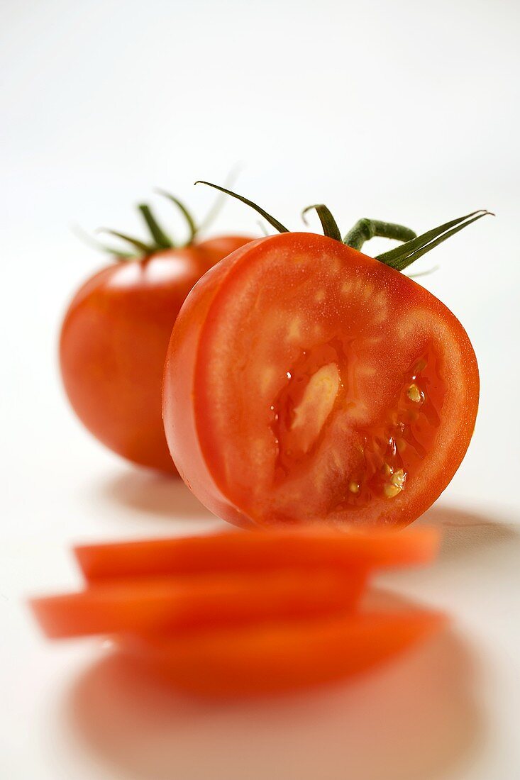 Two tomatoes, one partly sliced