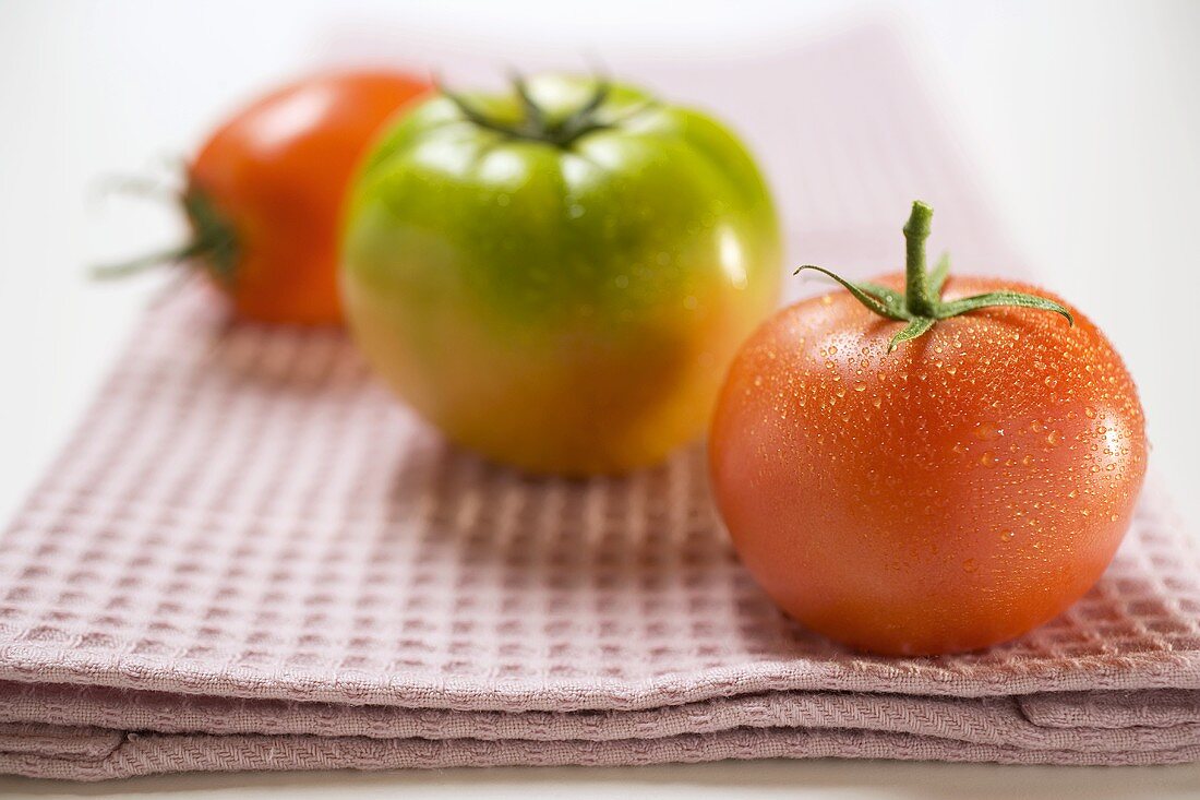 Three different tomatoes on tea towel