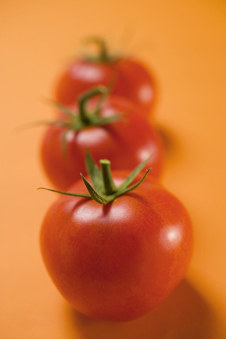 Drei Tomaten auf orangefarbenem Untergrund