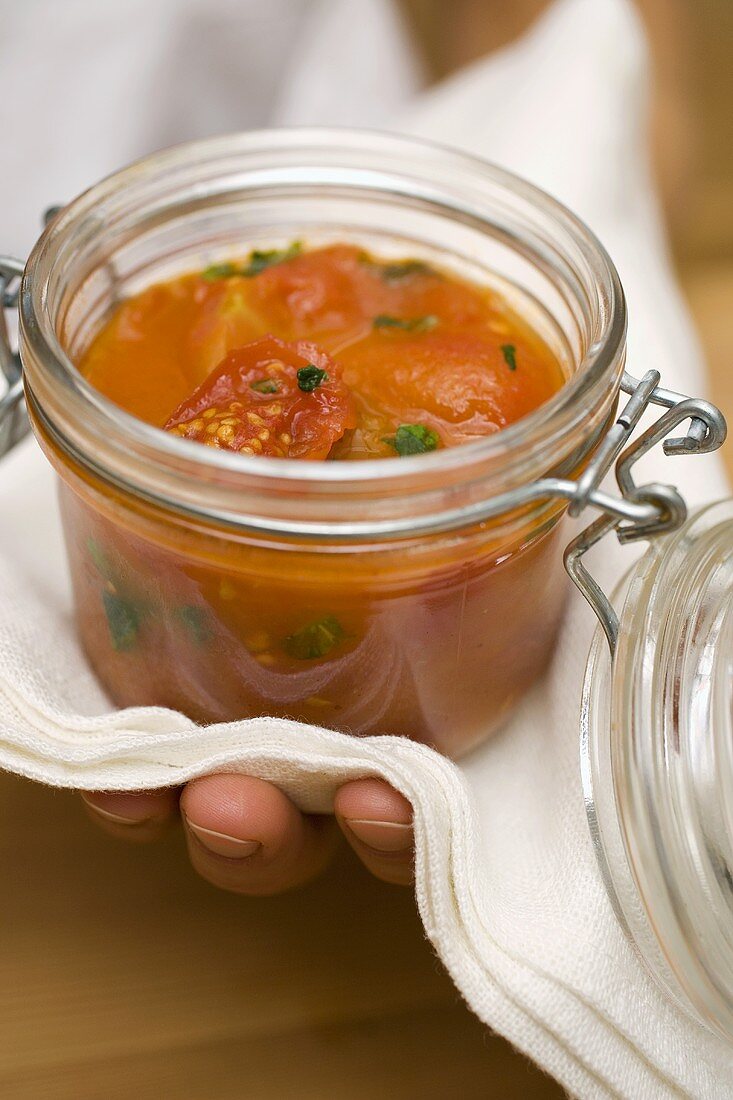 Hand holding preserving jar of tomato sauce