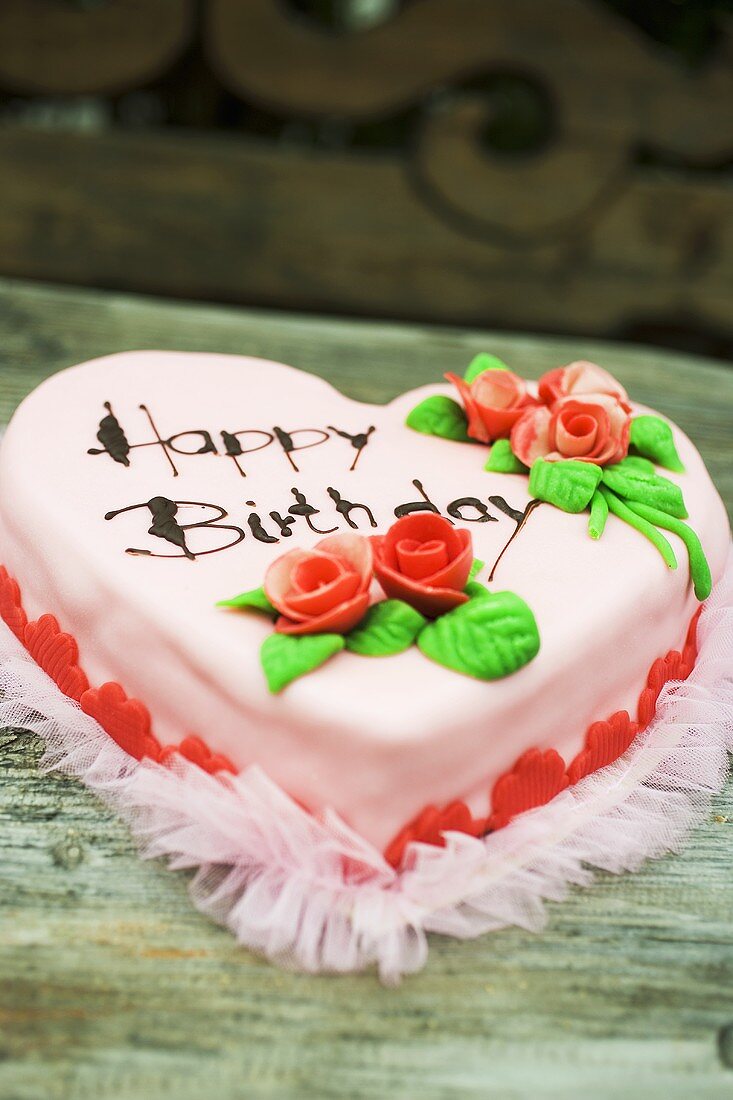 Pink heart-shaped birthday cake with marzipan roses