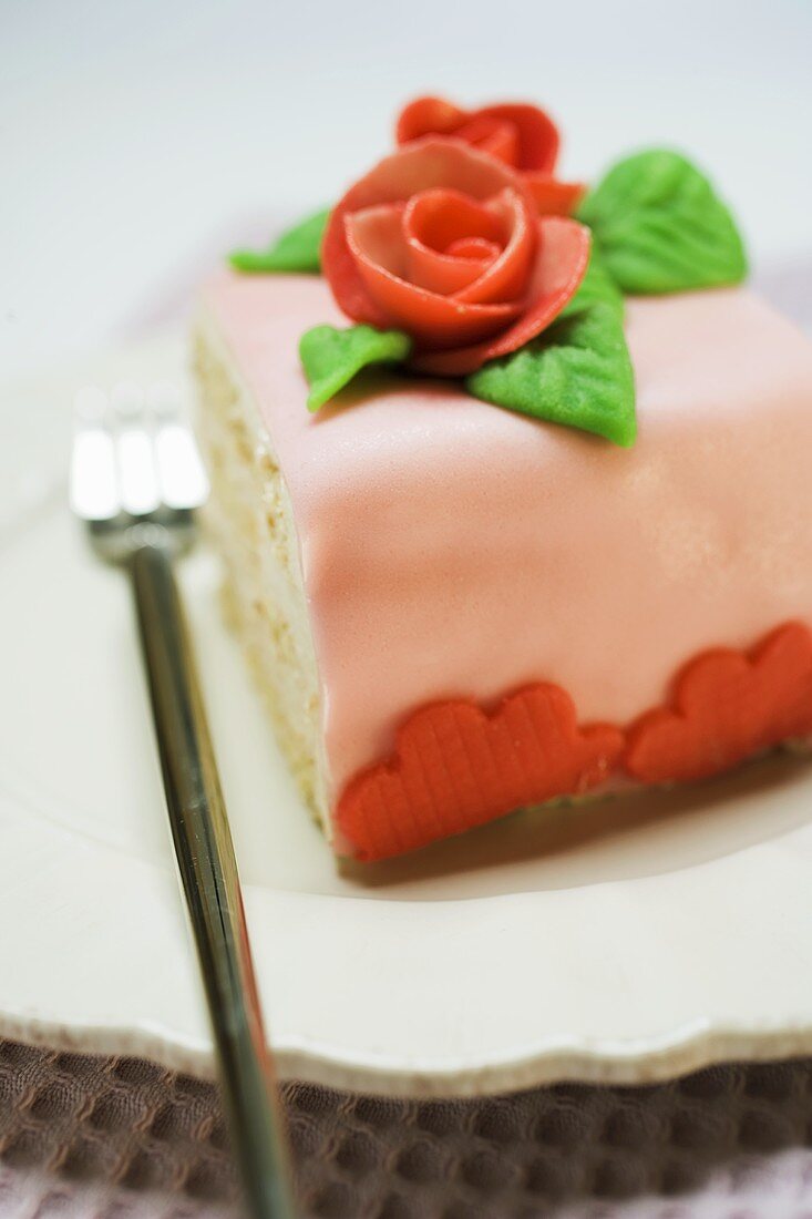 Piece of birthday cake with marzipan roses on plate
