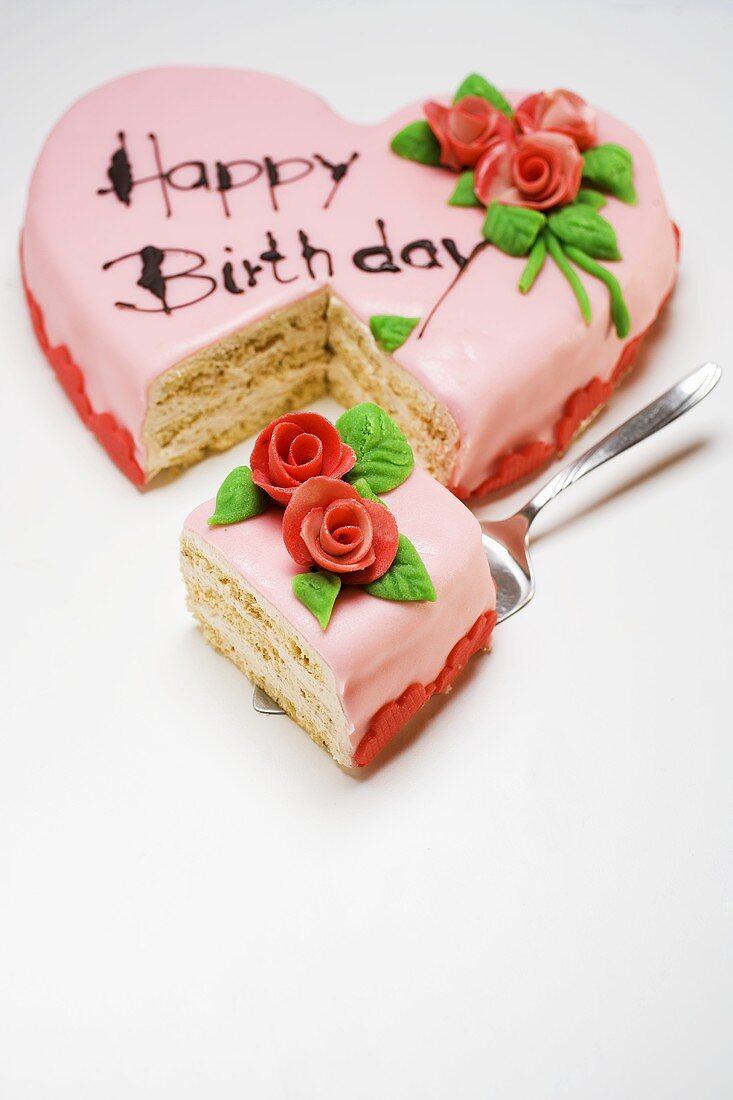 Herzförmige rosa Geburtstagstorte mit Stück auf Heber