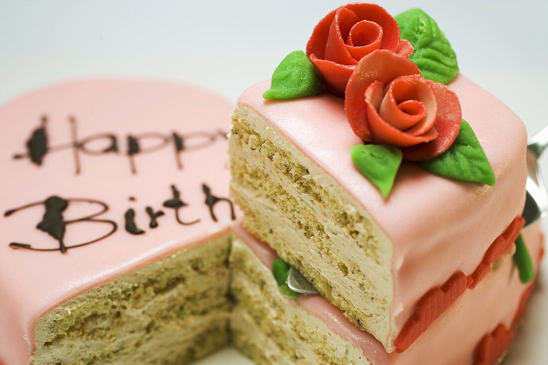 Pink heart-shaped birthday cake with piece on server