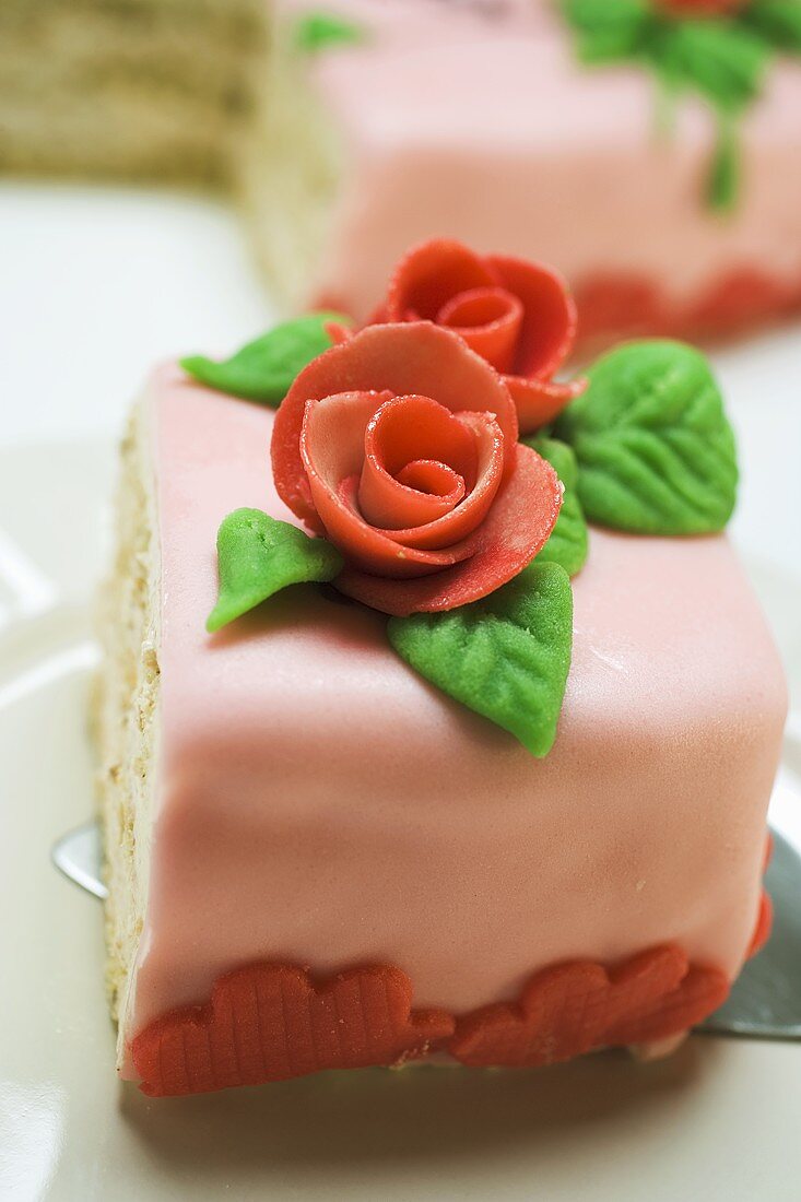 Piece of birthday cake with marzipan roses on cake server