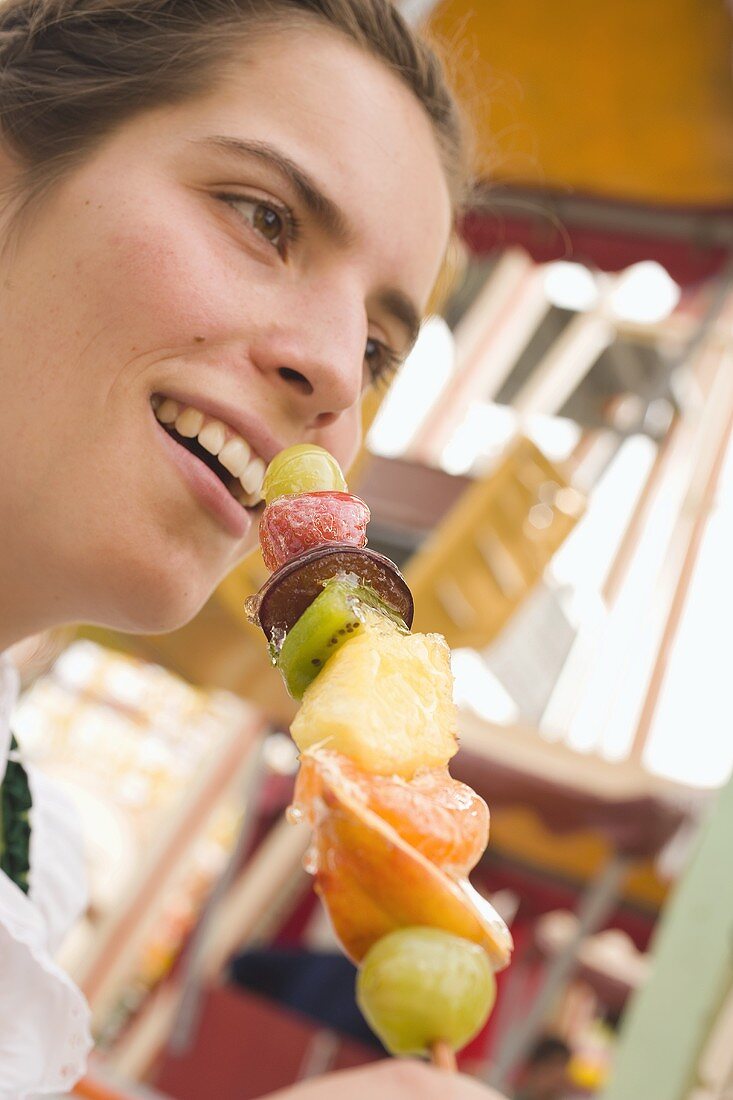 Frau hält kandierten Früchtespiess (München, Oktoberfest)