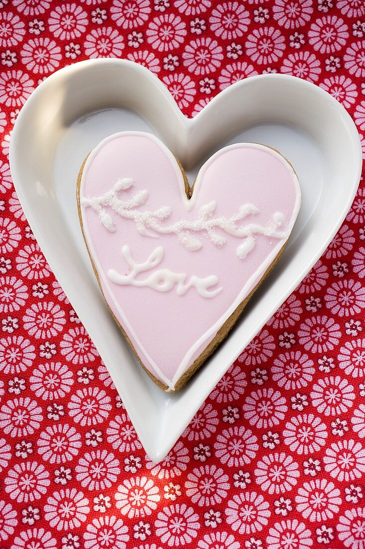 Heart-shaped biscuit with the word Love in white dish