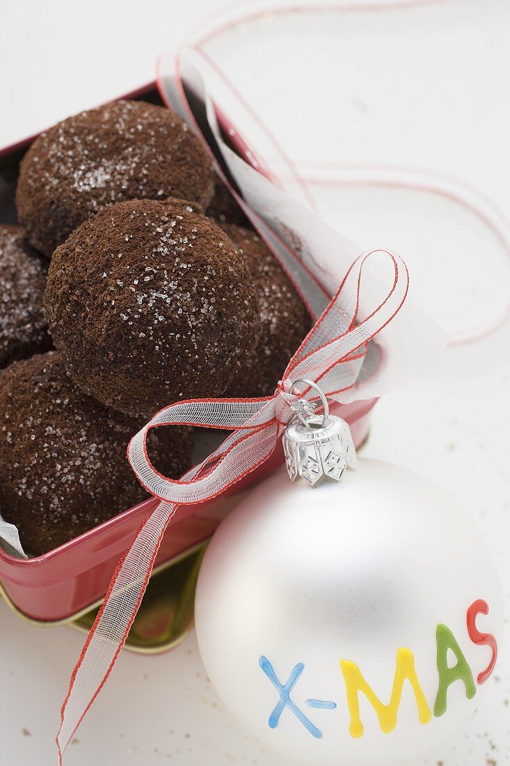 Chocolate kisses in biscuit tin, Christmas bauble beside it