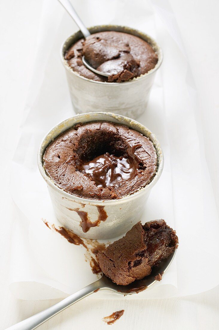 Two small chocolate soufflés filled with chocolate sauce