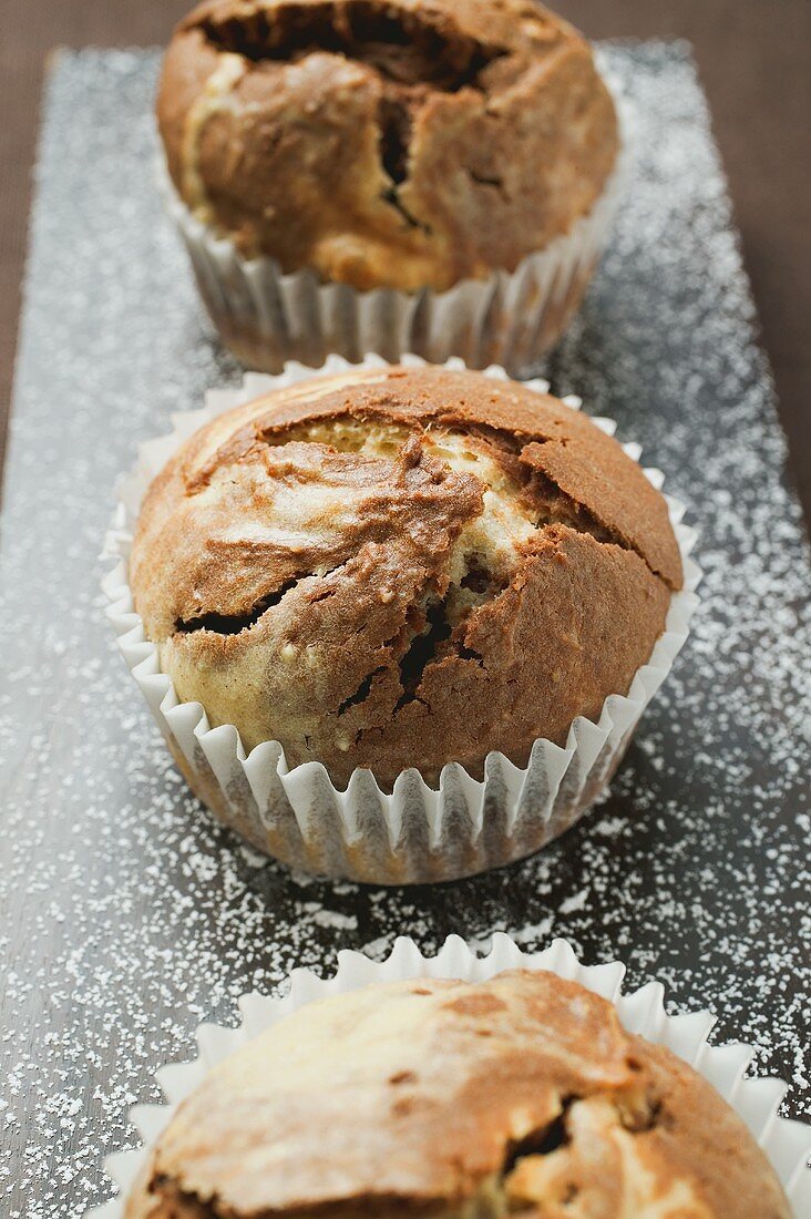 Drei Schoko-Vanille-Muffins in Papierförmchen