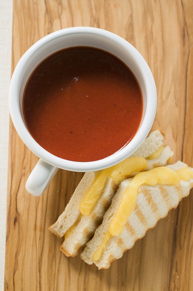 A cup of tomato soup & toasted cheese sandwiches on board