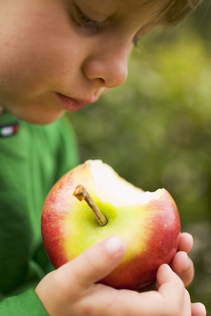 Child holding a Gala apple with a bite taken