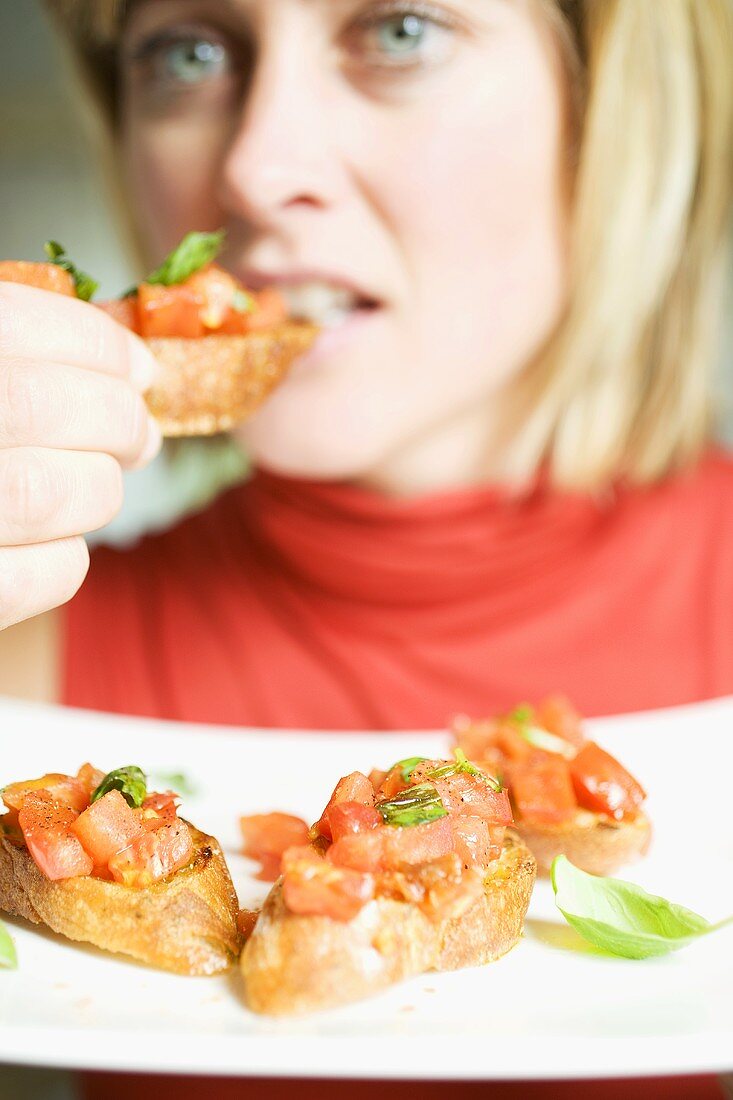 Frau isst Bruschetta mit frischem Basilikum