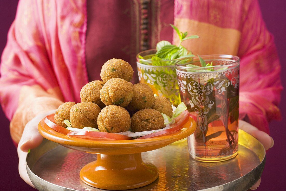 Frau hält Tablett mit Falafel (Kichererbsenbällchen) und Tee