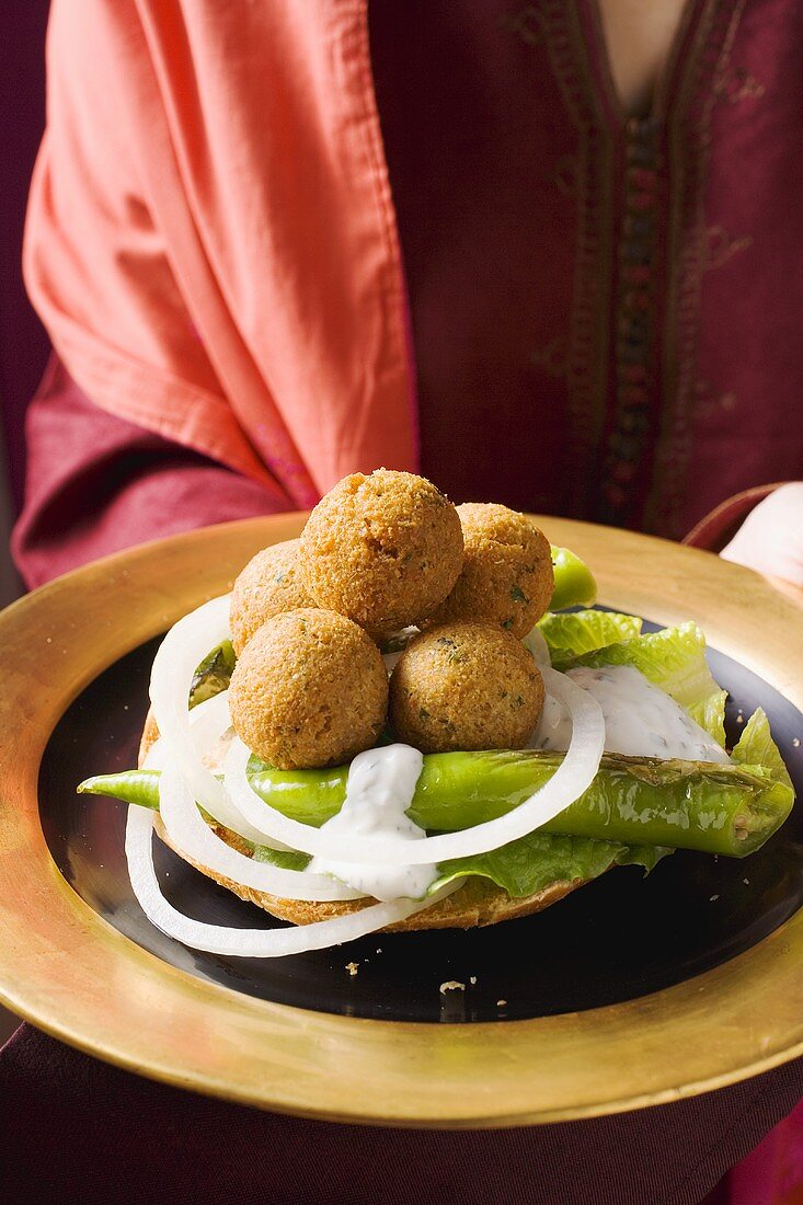 Woman serving falafel (chick-pea balls) with vegetables