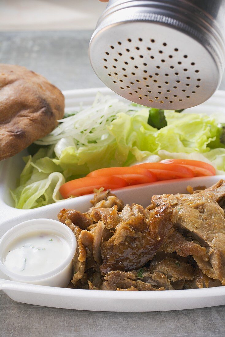 Döner Kebab in Lunchbox mit Gewürz bestreuen
