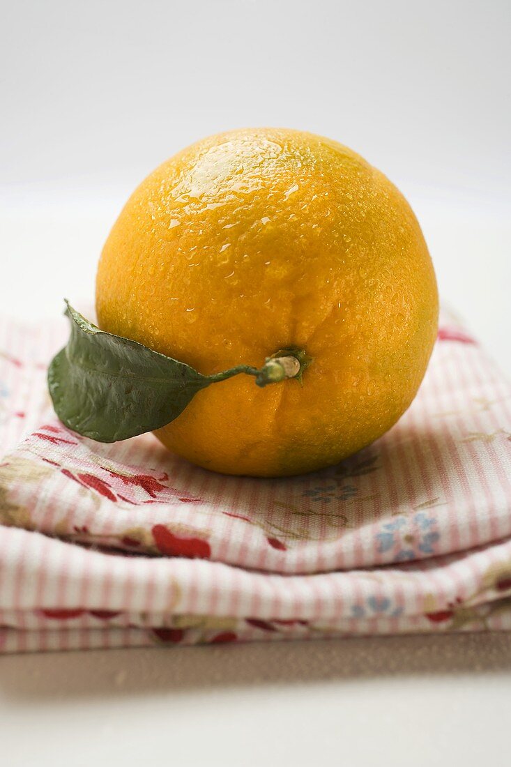 Orange mit Blatt auf Tuch