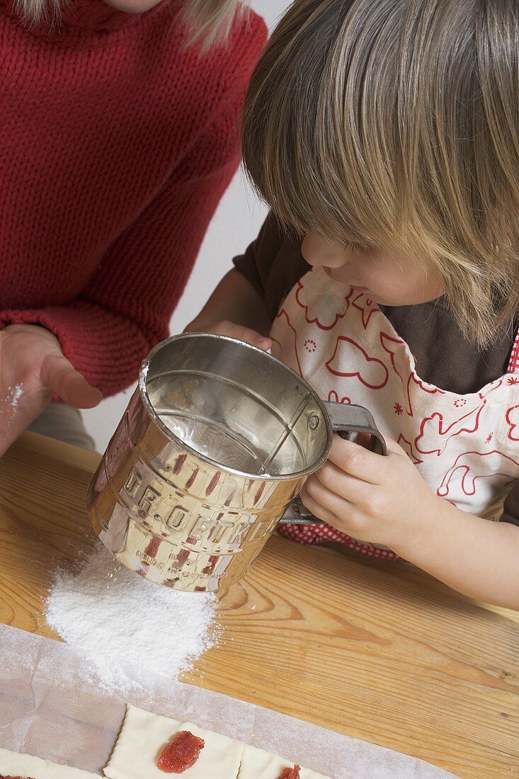 Small boy sieving flour