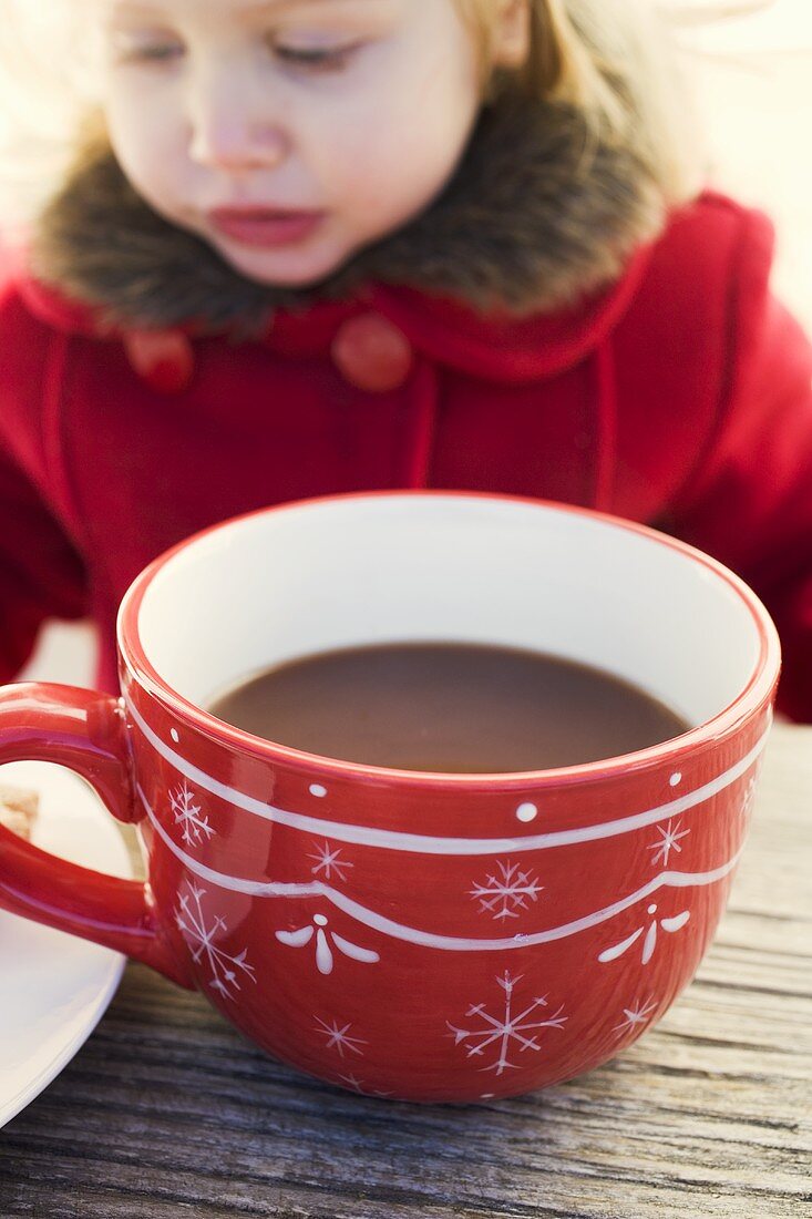 Small girl behind large cup of cocoa