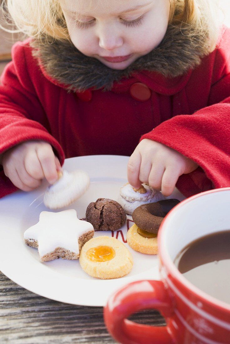 Kleines Mädchen nimmt Weihnachtsplätzchen vom Teller