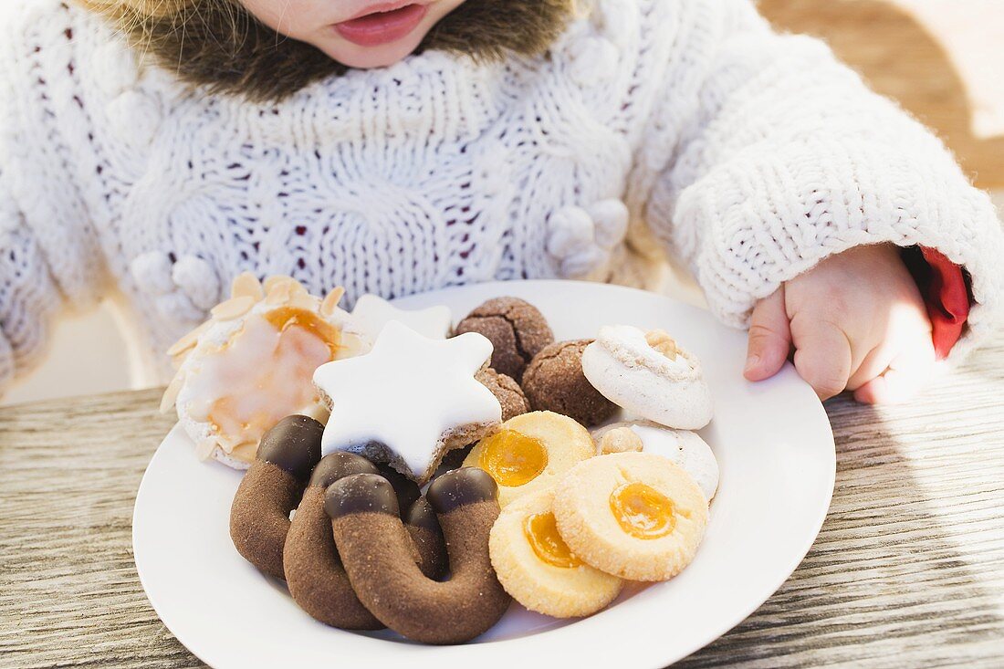 Kleines Mädchen mit Weihnachtsplätzchen auf Teller