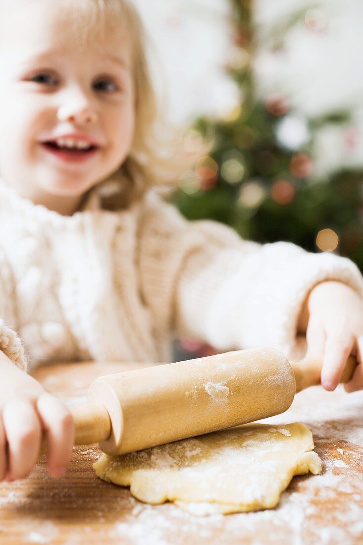 Kleines Mädchen rollt Teig aus (weihnachtlich)