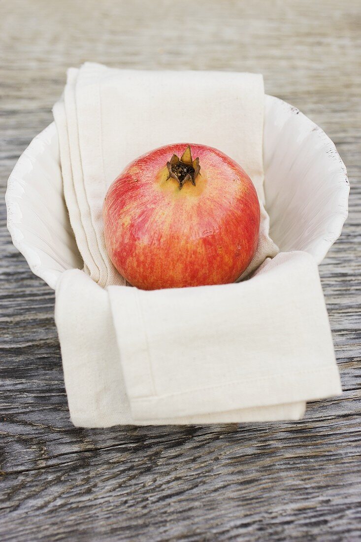 Granatapfel auf Tuch in weisser Schale