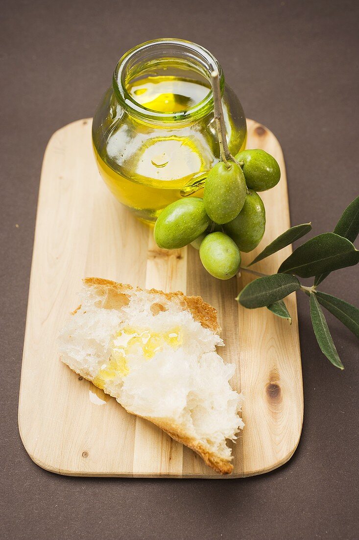 Grüne Oliven am Zweig, Weißbrot und Olivenöl